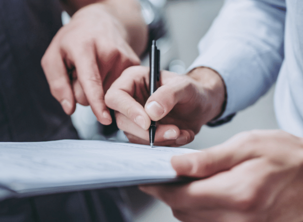 Zwei Personen füllen gemeinsam ein Formular auf einem Klemmbrett aus