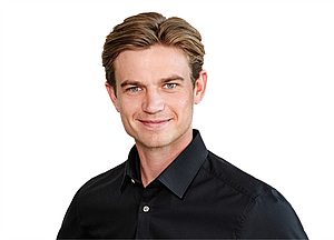 Porträt eines lächelnden Mannes im schwarzen Hemd vor weißem Hintergrund