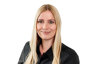 Porträt einer Frau mit langen glatten blonden Haaren und schwarzer Bluse vor weißem Hintergrund.