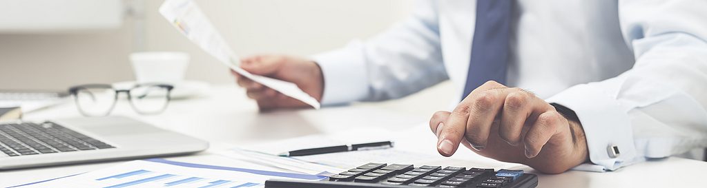 Rechnungen mit GPS-Ortung belegen Ein Mann bearbeitet unterlagen und rechnet mit einem Taschenrechner. Besser fakturieren mit GPS-Ortung von geoCapture