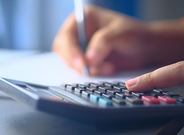 Close-up of a hand typing on a calculator